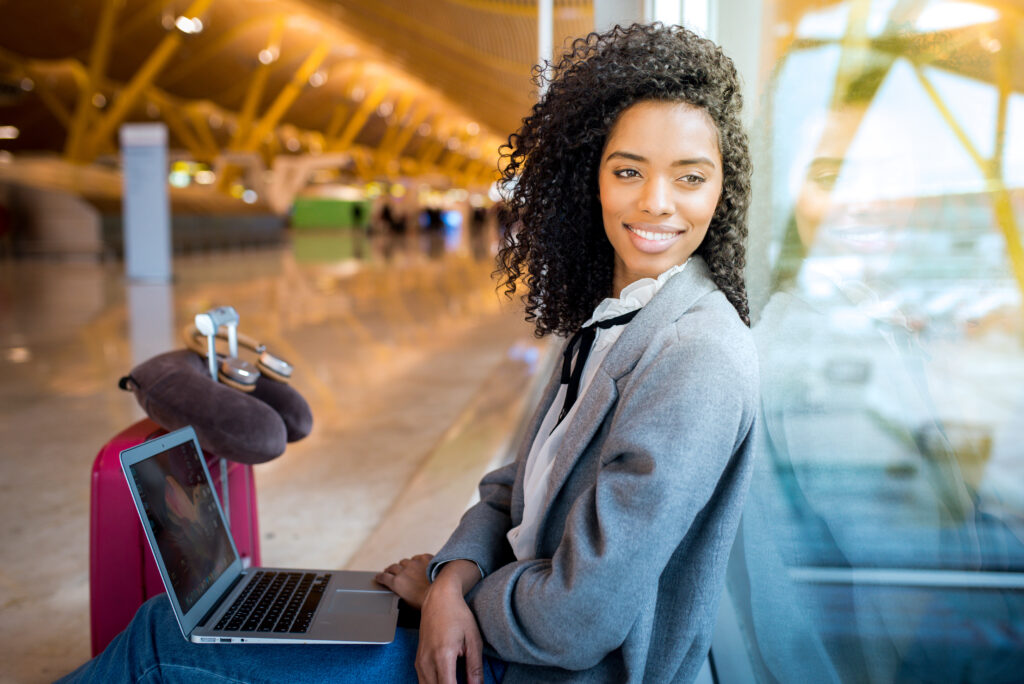 woman working with laptop at the airport waiting at the window