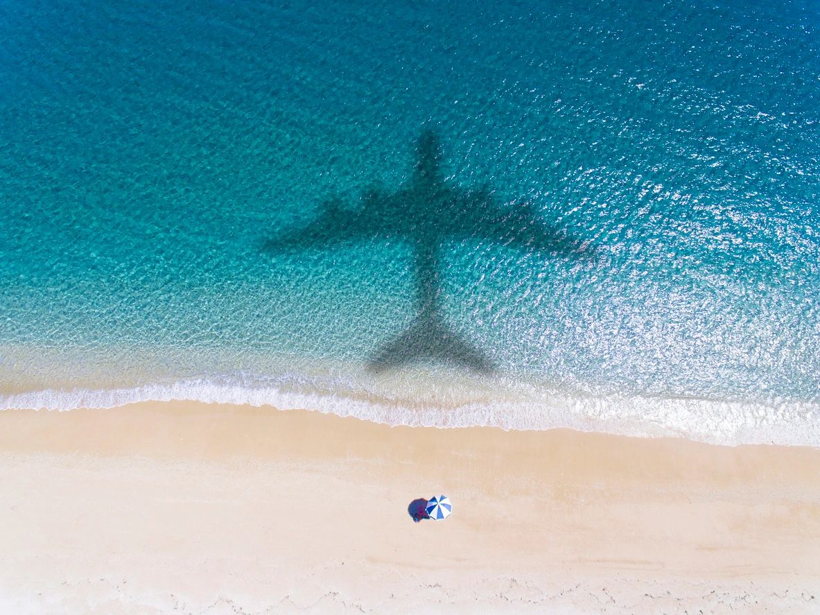 shadow of a plane flying over the ocean near a beach