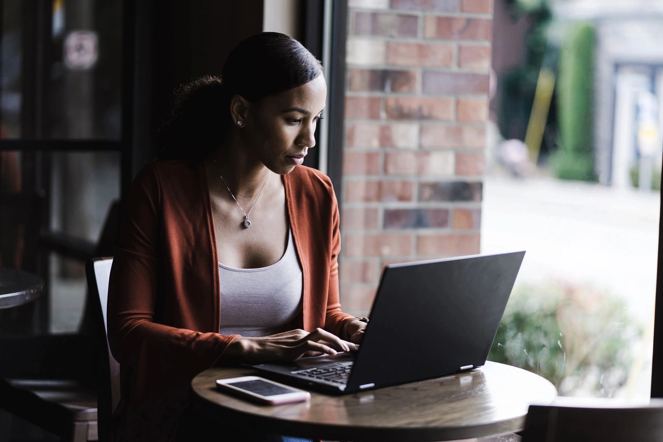 Woman sitting inside a cafe with her laptop booking travel reservations