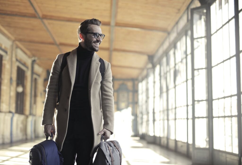 Traveler walking confidently with luggage in a bright station.